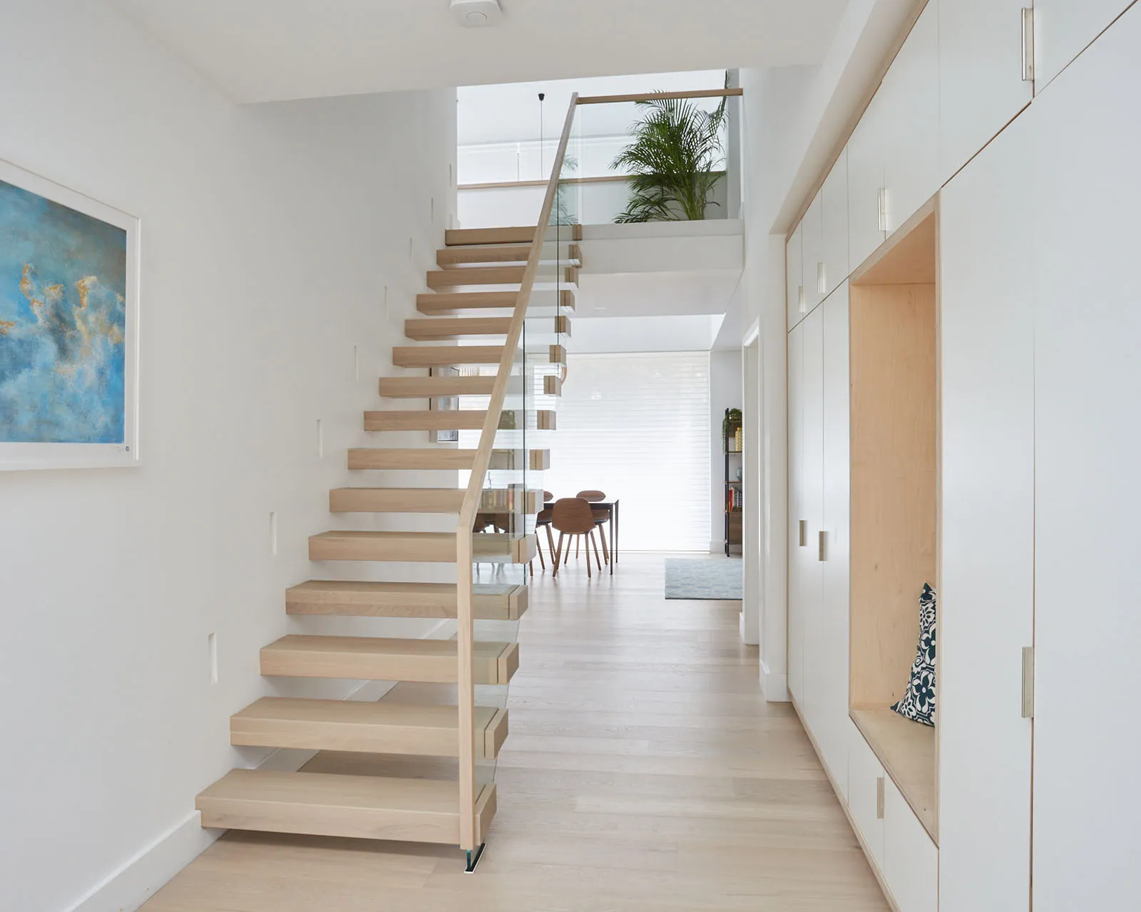 Straight floating staircase connecting two floors in an open plan area
